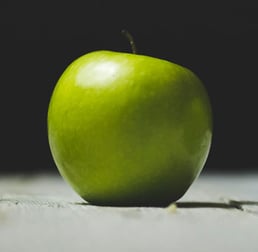 Pomme verte posée sur une surface en bois, avec un arrière-plan sombre